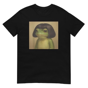 Puede incluir: Camiseta negra con una imagen cuadrada de una rana verde con un corte de pelo bob negro. La rana tiene ojos grandes y marrones y una expresión neutra. La obra de arte tiene un estilo pictórico con sombreado suave y una estética vintage.