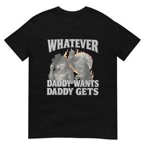 Może przedstawiać: Czarna koszulka z napisem „WHATEVER” nad frazą „DADDY WANTS DADDY GETS”. Grafika przedstawia dwa antropomorficzne wilki, z których jeden ma na sobie kapelusz kowbojski, na tle pełni księżyca.