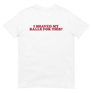Puede incluir: Camiseta blanca con el texto rojo "I SHAVED MY BALLS FOR THIS?" impreso en el pecho. La camiseta está hecha de un material suave y tiene cuello redondo.