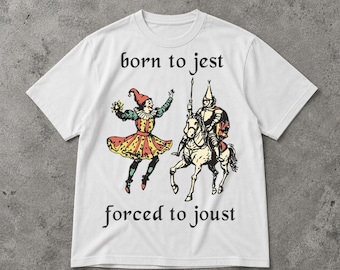 Puede incluir: Camiseta blanca con una ilustración medieval de un bufón y un caballero a caballo. El texto "born to jest" está encima de la imagen, y "forced to joust" debajo. El bufón lleva un atuendo colorido, y el caballero está armado.