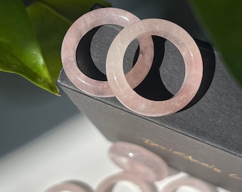 May include: A set of pink rose quartz rings, stacked on top of each other, in a black box. The rings are smooth and polished, with a subtle sparkle.