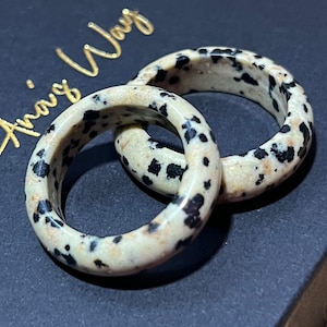 May include: Two rings made of dalmatian jasper, a white stone with black spots. The rings are stacked on top of each other.