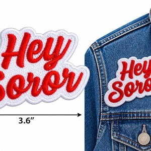 May include: An embroidered patch featuring the red text Hey Soror on a white background. The patch measures 2.2 inches in height and 3.6 inches in width. A second identical patch is shown attached to the chest area of a blue denim jacket.