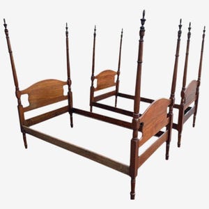 Könnte beinhalten: Ein Satz von drei antiken Holzbetten mit Himmelbett. Jedes Bett hat ein Kopfteil mit gewölbter Oberseite und vier hohen, schlanken Pfosten. Die Betten sind aus dunkelbraunem Holz gefertigt und haben ein klassisches Design.
