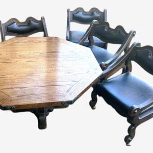 May include: An octagonal wooden dining table with four matching chairs. The table has a light brown finish and dark trim. The chairs have dark wooden frames and black leather seats and backs. A classic dining set.