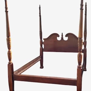 Può includere: Un telaio per letto a baldacchino in legno scuro. La testiera ha una parte superiore curva con intagli decorativi. I pali sono alti e ornati, con dettagli scolpiti. Il telaio del letto è progettato per ospitare un materasso e un sommier.