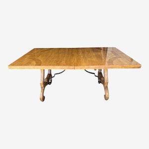May include: A rectangular wooden table with a light brown finish. The table has ornate, curved legs and a dark metal support structure. The table appears to be approximately 60 inches long and 36 inches wide.
