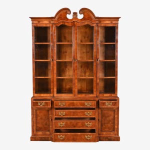 Puede incluir: Un mueble de madera antiguo con puertas de cristal y varios cajones. El mueble es de madera de tonos cálidos, con herrajes de latón y una parte superior decorativa. El diseño es tradicional, adecuado para exhibir objetos de colección o almacenamiento.