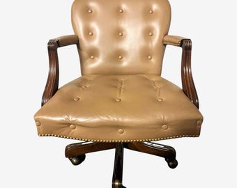 May include: A vintage office chair with a tan leather seat and back, featuring button tufting. The chair has dark wooden armrests and a wooden base with casters. The overall design is classic and elegant, suitable for a home office or study.