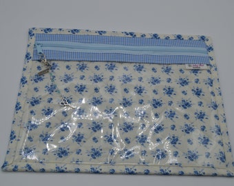 May include: A clear plastic zippered pouch with a blue and white floral print. The pouch has a blue and white checkered fabric trim and a zipper closure. A silver charm with a pair of scissors is attached to the zipper pull.