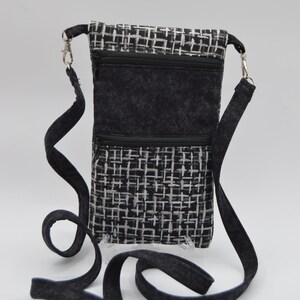 May include: A black and white patterned crossbody bag with a black strap. The bag has a zippered closure and multiple compartments.