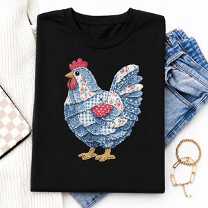 May include: Black crew neck t-shirt featuring a patchwork chicken design. The chicken is made of blue floral, polka dot, and gingham fabrics with a red comb and wattle. Gold-colored chicken feet complete the design. The shirt is paired with denim jeans and gold jewelry.