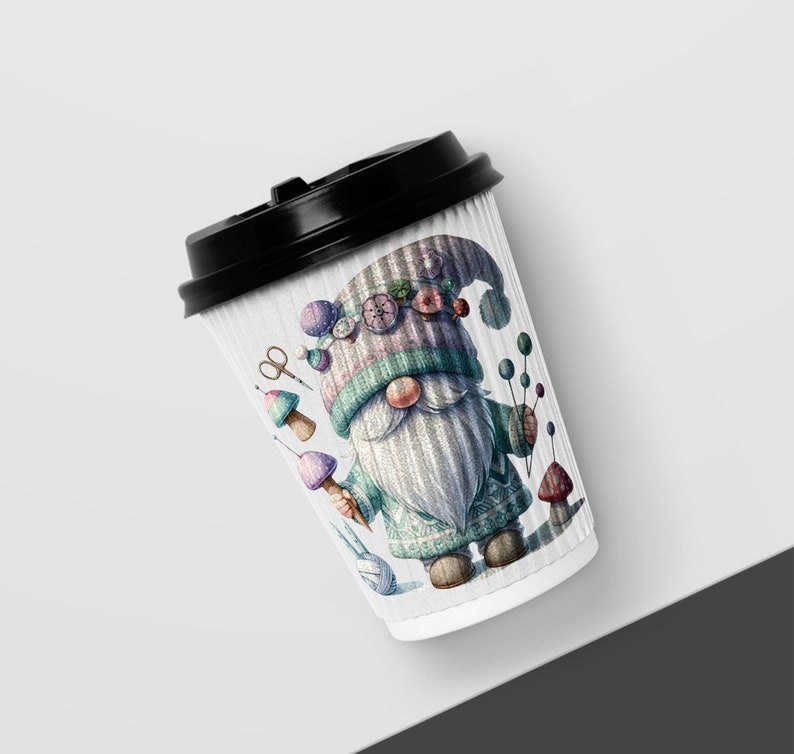 May include: A white paper coffee cup with a black lid features a colorful illustration of a gnome wearing a hat with buttons and holding a mushroom. The gnome is surrounded by other mushrooms, yarn, and a pair of scissors.