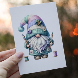 May include: A whimsical gnome illustration with a blue, green, and pink knitted hat, holding two pencils and surrounded by spools of thread.