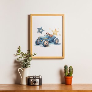 Op de afbeelding: Een ingelijst aquarel-illustratie van een blauwe speelgoedauto met twee sterren, een blauwe en een gele, op een witte achtergrond.