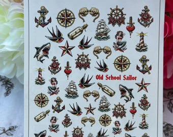 May include: A rectangular sheet of temporary tattoos featuring various nautical and traditional tattoo designs including anchors, compasses, ships, sharks, mermaids, lighthouses, swallows, and bottles with messages. The text Old School Sailor is printed.