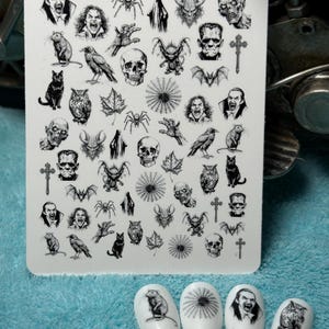 Puede incluir: Una placa de estampado de arte de uñas blanca con varios diseños temáticos de Halloween, incluyendo murciélagos, calaveras, arañas y caras de vampiros. Cuatro puntas de uñas blancas están decoradas con diseños a juego. Los diseños son en negro.