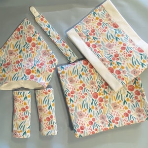 Conjunto de presente para bebê recém-nascido com tema floral: babador, cobertor para receber, almofada para arrotos, prendedor de chupeta e protetores de cinto de segurança para carro