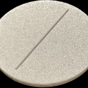 May include: A white round plastic base with a textured surface and a single line across the center.