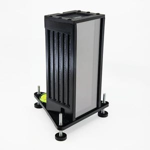 May include: A black and silver rectangular device with a ridged side panel and a clear, light-colored panel. The device sits on a black triangular base with adjustable feet and a yellow level. The device is designed for a specific purpose.