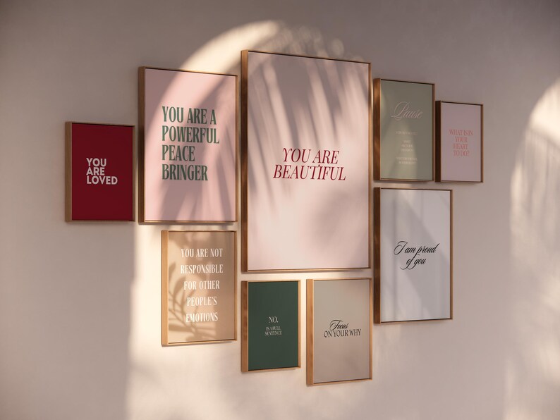 May include: A wall gallery featuring eight framed prints with inspirational messages in various colors, including pink, green, and red. The prints feature phrases like "You are loved", "You are a powerful peace bringer", "You are beautiful", and "Focus on your why".