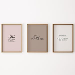 May include: Three framed motivational posters with gold frames. The posters have a light pink, light brown, and white background. The text on the posters reads "You can do hard things", "Focus on your why", and "Breathe. You're going to be ok."