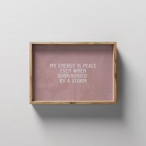 May include: A framed print with a pink background and white text that reads "My energy is peace even when surrounded by a storm."