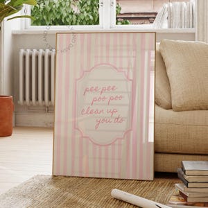 May include: A rectangular wall art print featuring a light pink and white vertical striped background. Centered is a decorative frame containing the text "pee pee poo poo clean up you do" written in a cursive pink font on a white background.