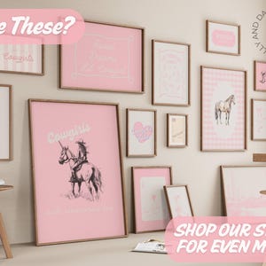 May include: A collection of framed art prints in various sizes, featuring a pink and white color scheme. The prints include text and illustrations of horses, hearts, and the word "Cowgirls". The wall art is displayed in a room setting.