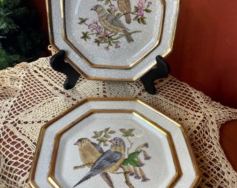 May include: Two octagonal decorative plates with gold trim. Each plate features a detailed illustration of birds perched on flowering branches. The plates have a white background with a crackle effect.