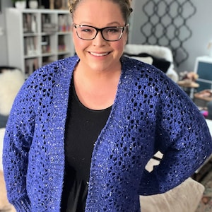 May include: A blue crocheted cardigan with a sparkly thread. The cardigan has a loose fit and a V-neck.