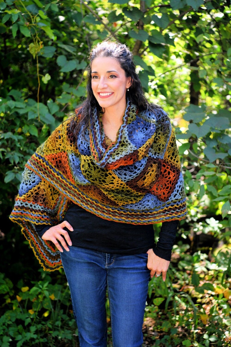Handcrafted crochet shawl with earthy tones displayed on a model, showcasing intricate motifs in rich autumn color pallet. Enchanted Crochet Shawl by Marly Bird