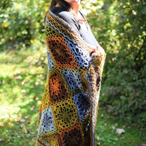 Handcrafted crochet shawl with earthy tones displayed on a model, showcasing intricate motifs in rich autumn color pallet. Enchanted Crochet Shawl by Marly Bird