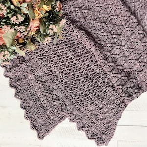 May include: A purple knitted shawl with a lacy pattern. The shawl is folded in half and has a scalloped edge.