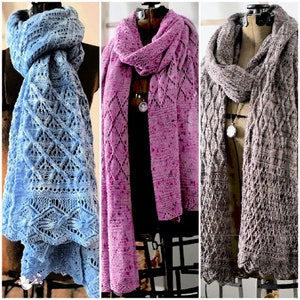 A colorful display of three intricate lace knit shawls in shades of blue, pink, and brown, elegantly draped over mannequin busts to showcase the patterns and craftsmanship as unique handmade gifts. Stitch Switch vol 2 knit shawl collection Marly Bird