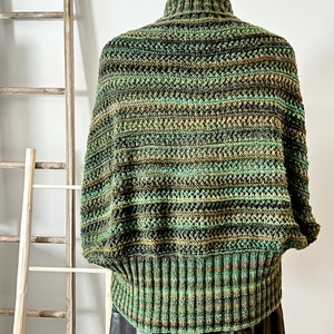 An elegantly draped, hand-knit cocoon cardigan displayed on a mannequin, showcasing rich hues of green with a subtle variegated pattern, chunky ribbed collar, and a large decorative button at the front. Marly Bird Know Your Worth Knit Cocoon Cardigan