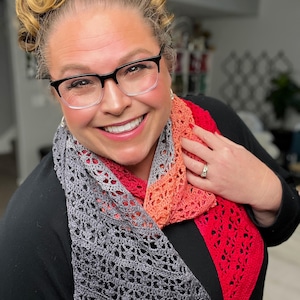 May include: A woman wearing a black shirt and a crocheted scarf with a gradient of gray, orange, and red.