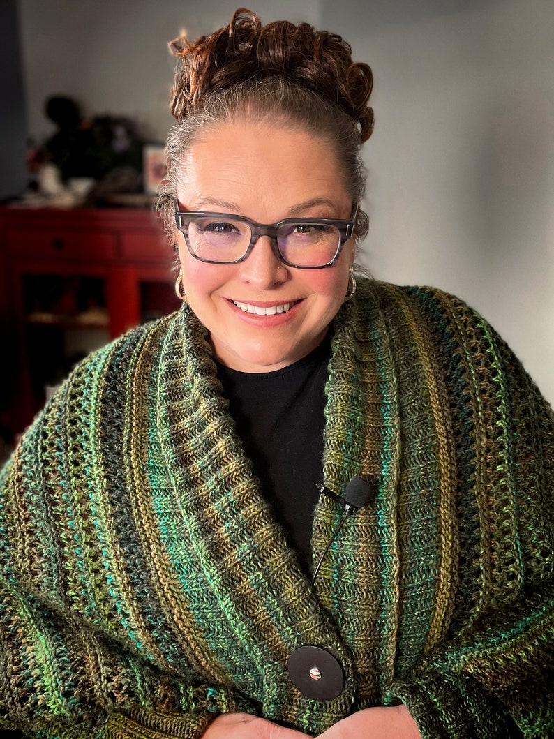 An elegantly draped, hand-knit cocoon cardigan displayed on a Marly Bird, showcasing rich hues of green with a subtle variegated pattern, chunky ribbed collar, and a large decorative button. Marly Bird Know Your Worth Knit Cocoon Cardigan