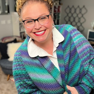 May include: A woman wearing a teal, purple, and green striped cardigan with a white collared shirt underneath.