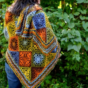 Handcrafted crochet shawl with earthy tones displayed on a model, showcasing intricate motifs in rich autumn color pallet. Enchanted Crochet Shawl by Marly Bird