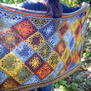 Handcrafted crochet shawl with earthy tones displayed on a model, showcasing intricate motifs in rich autumn color pallet. Enchanted Crochet Shawl by Marly Bird