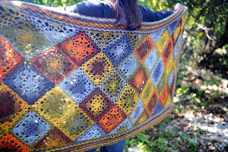 Handcrafted crochet shawl with earthy tones displayed on a model, showcasing intricate motifs in rich autumn color pallet. Enchanted Crochet Shawl by Marly Bird