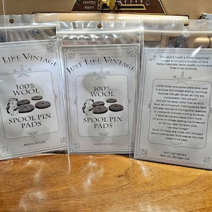 Könnte beinhalten: Drei Packungen mit 100 % Woll-Spulen-Pads, hergestellt in den USA. Die Packungen sind mit "Just Like Vintage" beschriftet und zeigen ein Vintage-Nähmaschinen-Design. Der Text auf der Verpackung lautet: "Sie brauchen keine Zeitmaschine! Vintage ist nicht nur eine Frage der Zeit. Bessere Materialien, bessere Qualitätskontrolle und Stolz auf unsere Produkte."