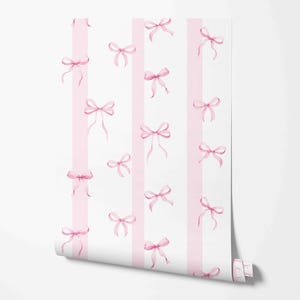 May include: A roll of wallpaper featuring a repeating pattern of light pink watercolor bows scattered across vertical white and pale pink stripes. The design displays a soft color palette with delicate ribbon illustrations throughout.