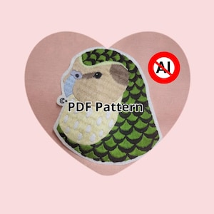Peut inclure: Un écusson de perroquet conure à joues vertes avec le texte "PDF Pattern" est présenté sur un fond rose en forme de cœur. L'écusson présente un design détaillé avec des couleurs vertes, marron et bleues. Un symbole rouge "no AI" est également présent.