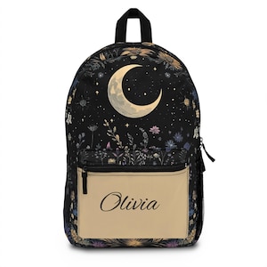 Può includere: Zaino nero con un design celeste con una luna crescente, stelle e accenti floreali. La tasca frontale è beige con il nome "Olivia" in corsivo. Lo zaino ha una maniglia superiore e una cerniera nere.
