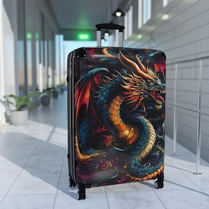 May include: A rolling suitcase featuring a vibrant, detailed illustration of a dragon with scales in shades of blue, orange, and yellow. The dragon has large wings and an open mouth, set against a dark, swirling background. It has a black frame and wheels.