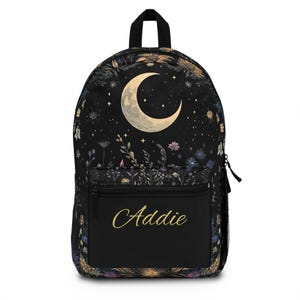 Può includere: Zaino nero con una luna crescente e un design floreale. Lo zaino ha una tasca con cerniera sul davanti con il nome "Addie" scritto in lettere dorate.