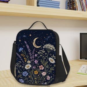 May include: A black rectangular crossbody bag featuring a printed design of a crescent moon and stars against a dark navy night sky, layered over a field of colorful wildflowers including daisies, lavender, and cornflowers with green stems.