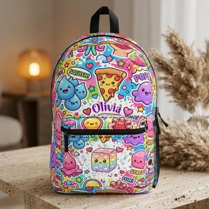 Op de afbeelding: Een rugzak met een levendig, veelkleurig patroon van kawaii-stijl figuren, waaronder een pizzapunt, waterdruppels en een regenboogkubus. De naam Olivia staat in paars schrift in het midden gedrukt. Het heeft een zwarte rits en een zijvak van gaas.